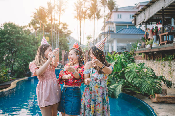 3 asian chinese female playing with confetti at the poolside of the backyard of the house during birthday celebration event in the evening - garden decoration stock pictures, royalty-free photos & images