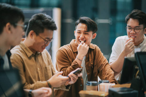 4 asian chinese eating popcorn waiting for movie show time at bar counter lobby lounge beside ticketing counter in cinema movie theater - junk food stock pictures, royalty-free photos & images