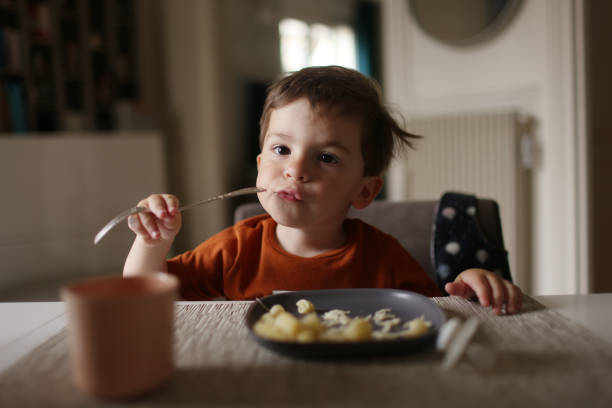 a 3 year old little boy having his lunch at home - food stock pictures, royalty-free photos & images