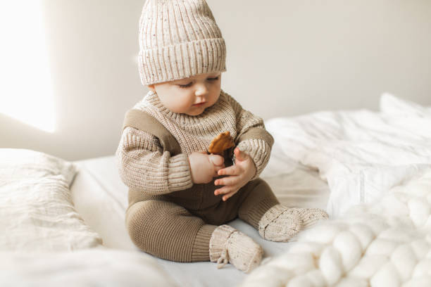 a 5 month old baby boy in cotton knitwear laying on a bed. - fashion stock pictures, royalty-free photos & images