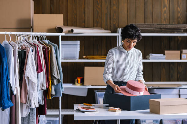 a beautiful businesswoman packing a hat for shipping in her store - fashion stock pictures, royalty-free photos & images