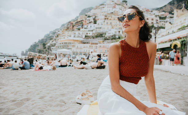 a beautiful woman enjoys lounging on a beach in positano, italy - travel stock pictures, royalty-free photos & images