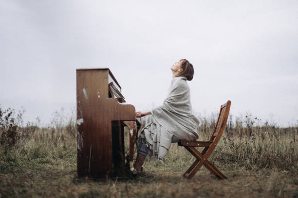 a beautiful woman is playing the piano with pleasure in a field in autumn - concert stock pictures, royalty-free photos & images