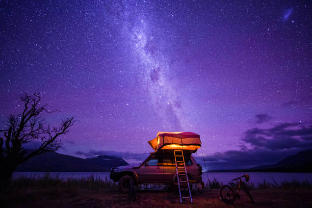 a camper van at nightfall near water body. - travel stockfoto's en -beelden