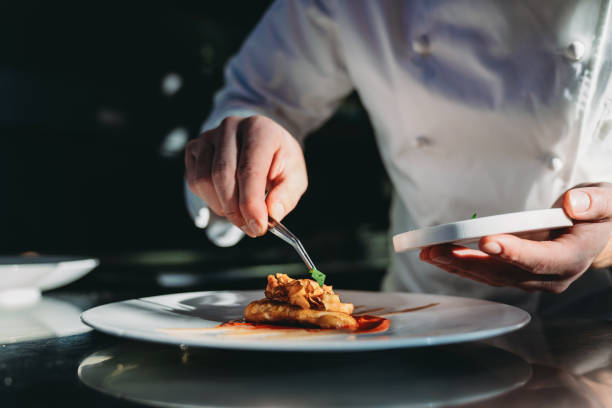 a chef is finishing the preparation of the plate - food stock pictures, royalty-free photos & images