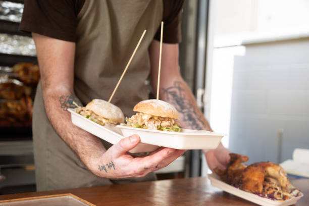 a chef serves two chicken burgers and a roast chicken from a food food truck - junk food stock pictures, royalty-free photos & images