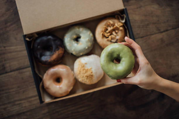 a choice of various delicious crafted donuts from a takeaway box - junk food stock pictures, royalty-free photos & images