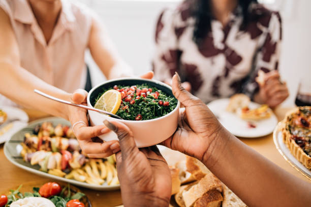 a close up view of an unrecognizable woman giving food to a caucasian female - food stock pictures, royalty-free photos & images