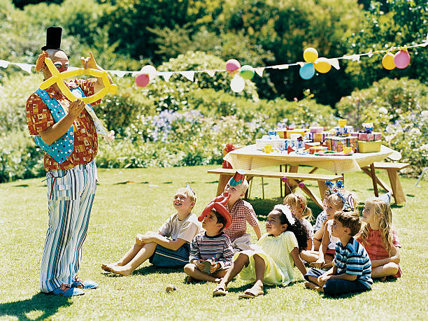 a clown amuses a medium group of children at a birthday party - garden decoration stock pictures, royalty-free photos & images