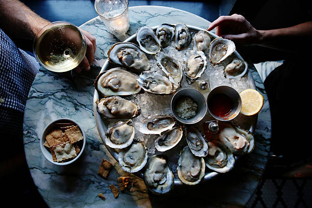 a couple enjoying raw oysters - food stock pictures, royalty-free photos & images