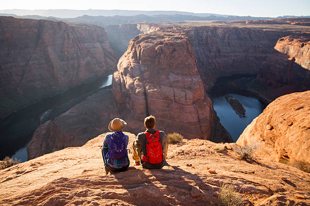 a couple hiking on the edge of a senic overlook. - travel stock pictures, royalty-free photos & images