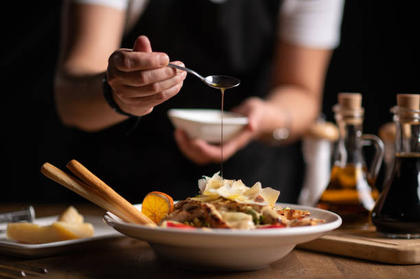 a female chef pouring sauce on salad - food stock pictures, royalty-free photos & images