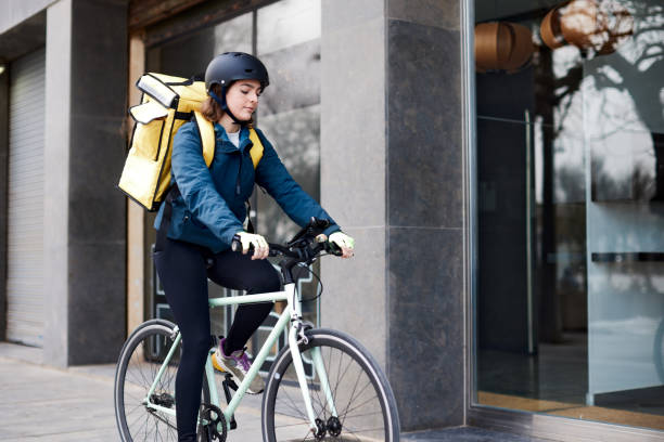 a female delivery person standing in front of a doorway. - junk food stock pictures, royalty-free photos & images
