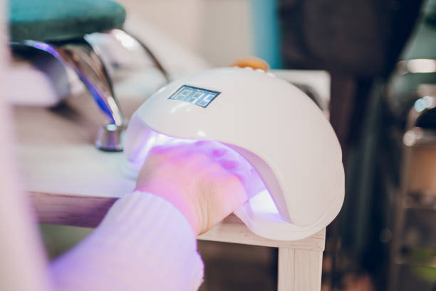 a hand inside a uv lamp for drying nail polish - nails art stock pictures, royalty-free photos & images