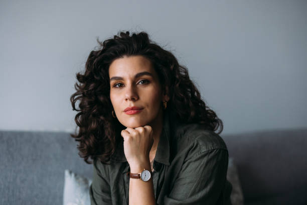 a happy beautiful businesswoman looking at camera while relaxing at home - hairstyle stock pictures, royalty-free photos & images