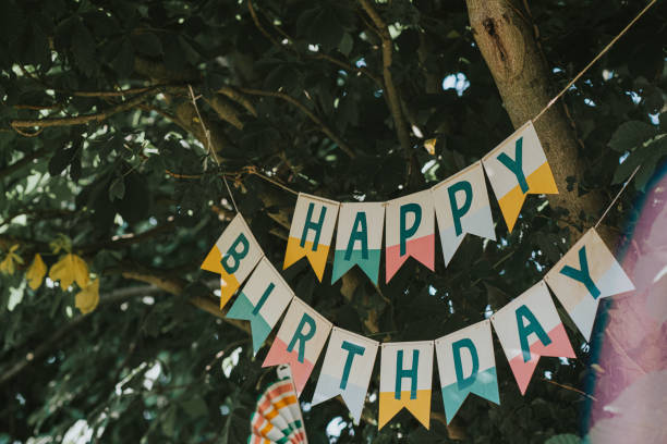 a 'happy birthday' banner hangs from a tree - garden decoration stock pictures, royalty-free photos & images