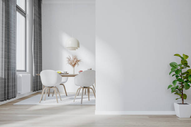a luxury modern (scandinavian style) dining room with a potted plant in front of a white blank wall and dining table and chairs, windows in the background - home decoration stock pictures, royalty-free photos & images