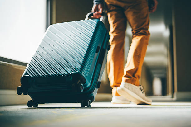 a man walks down the hotel corridor with luggage. - travel stock pictures, royalty-free photos & images