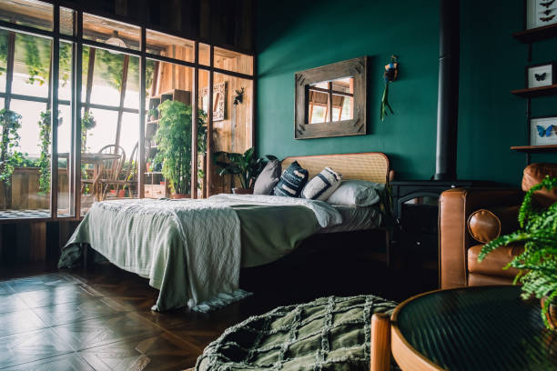 a stylish loft bedroom interior with brown coloured rattan furniture and wooden elements with dark green coloured wall. decorated with plants - home decoration stockfoto's en -beelden