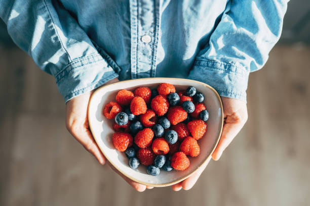 a woman holds a plate of fruits and berries in her hands - food stock pictures, royalty-free photos & images