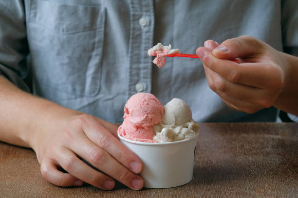 a young man, a guy eats ice cream in a cafe, cafeteria, in a chain of fast food restaurants. vegan ice cream in the hands of a high school student. vanilla and berry sherbet, dessert. the concept of rest and relaxation, vacat