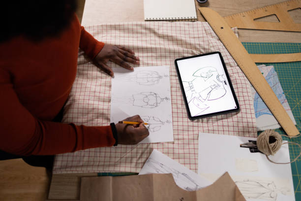 above view of black fashion designer sketching and using touchpad in a design studio. - fashion stock pictures, royalty-free photos & images