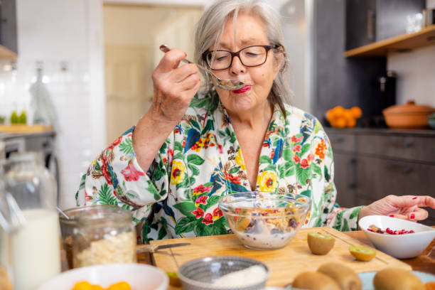 active senior woman is enjoying her healthy breakfast - food stock pictures, royalty-free photos & images