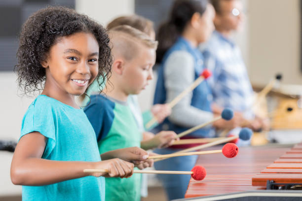 adorable little girl smiles for camera while playing xylophone - concert stock pictures, royalty-free photos & images