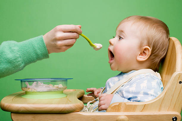 adult feeding baby - food stock pictures, royalty-free photos & images