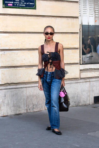 Adwoa Aboah wears a lace up top, blue jeans, black bag and sunglasses and black Chanel ballet shoes outside the Chloe show during the Womenswear...
