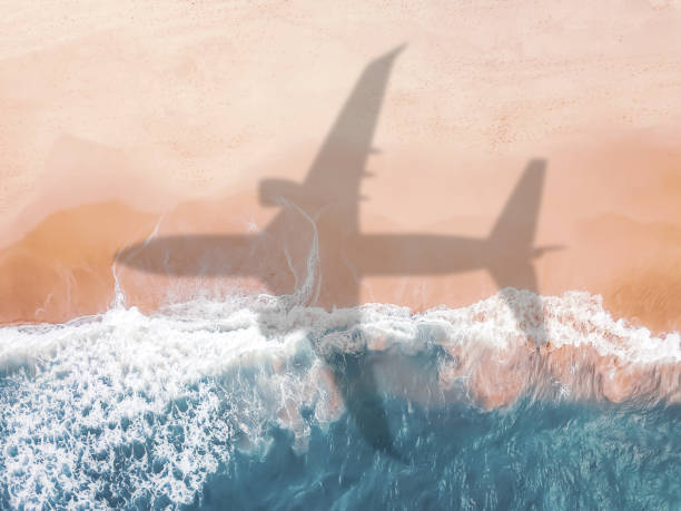 aerial view of an airplane shadow over a sandy beach. - travel stock pictures, royalty-free photos & images