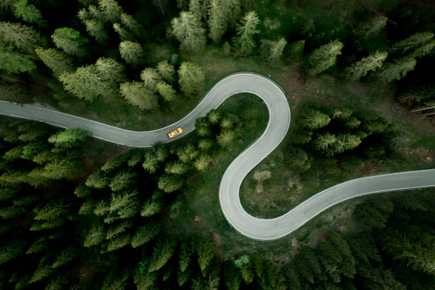 aerial view of car traveling on winding mountain road in a forest - travel stock pictures, royalty-free photos & images