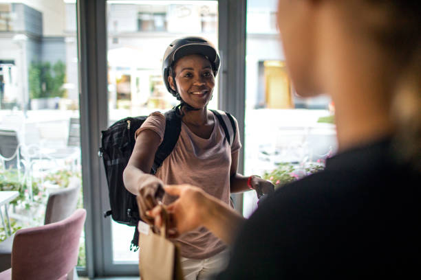 african delivery woman delivering package to customer - junk food stock pictures, royalty-free photos & images