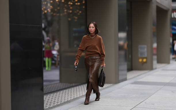 Aimee Song is seen outside Proenza Schouler show wearing golden Tiffany hardware necklace, brown wool pullover, brown leather skirt with matching...