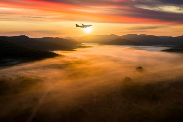 airplane over misty mountains at dawn - travel stock pictures, royalty-free photos & images