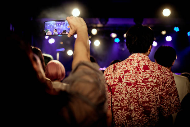 among the audience enjoying the concert, taking pictures with a smart phone. - concert stock pictures, royalty-free photos & images