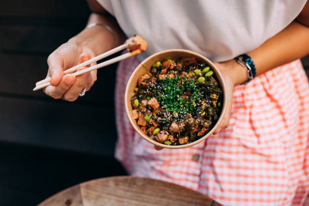an anonymous woman having outdoor lunch using chopsticks - junk food stock pictures, royalty-free photos & images