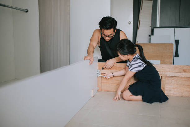 an asian chinese family moving house daughter helping her father assemble bed frame - home decoration stock pictures, royalty-free photos & images