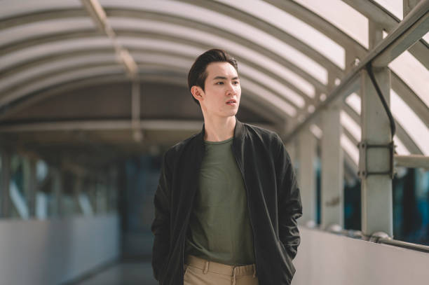 an asian chinese young man walking out from the sub way station in the day smiling - fashion stock pictures, royalty-free photos & images