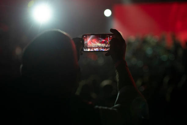 An attendee takes a photo with their smartphone as the musicians of Rockin'1000 perform live on September 30, 2021 in Milan, Italy. A free...