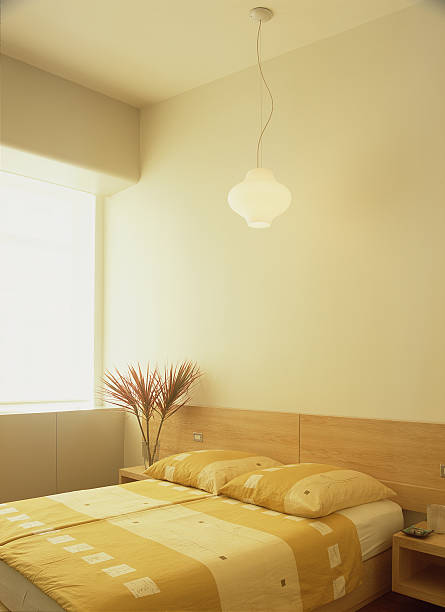 an elegant lamp is suspended from the ceiling above the bed in the bedroom - home decoration stock pictures, royalty-free photos & images