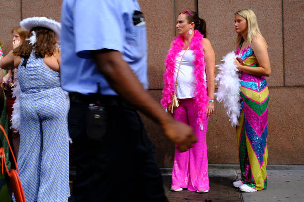 An employee walks past fans wearing themed outfits waiting in line for the Harry Styles Love On Tour 2022 concert at Madison Square Garden on August...