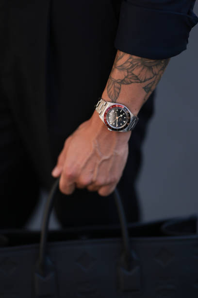 André Hellmundt seen wearing Olymp Hemd black buttoned shirt, matching Suit Supply black long suit pants, Tudor silver watch, MCM black leather logo...