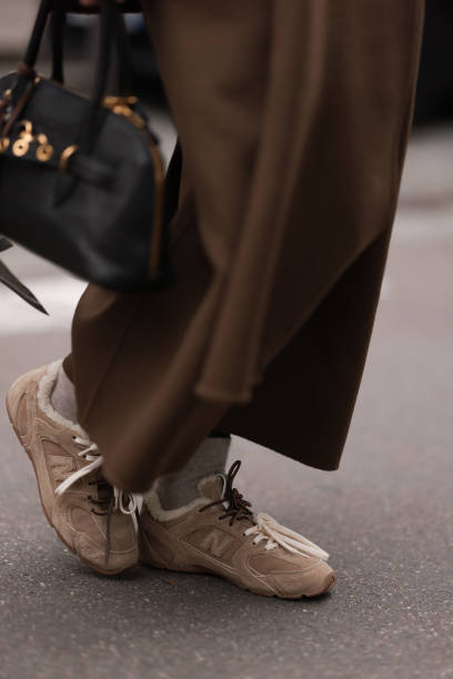 Anna Wein is seen wearing an ankle-length brown wool trench coat from Sandro, a rectangular black leather bag with gold details from Miu Miu, beige...