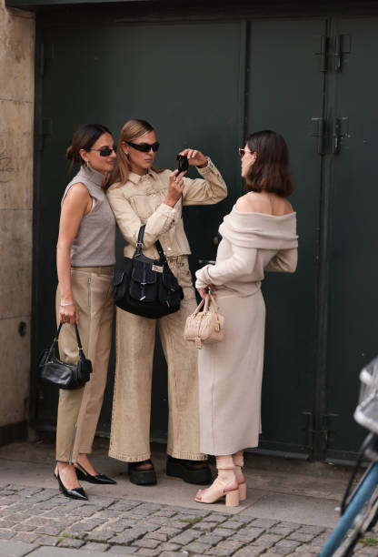 Anna Winter is seen wearing sunglasses with a fine black frame from Ray Ban, silver hoop earrings, a beige knitted tank top with turtleneck, two-tone...