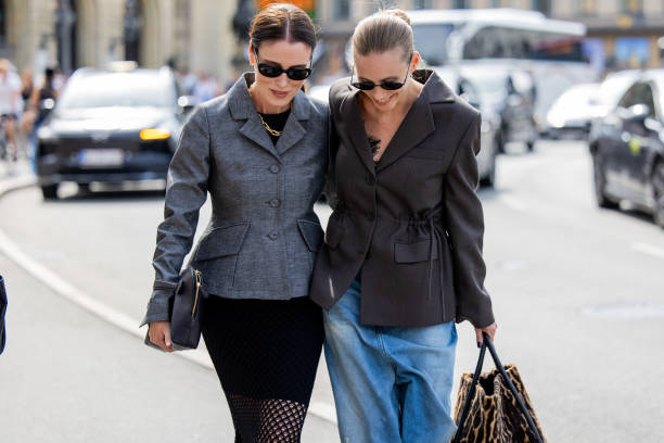 Annabel Rosendahl wears grey tailored jacket, black net skirt, bag, sunglasses & Tine Andrea wears grey tailored blazer, wide leg denim jeans, animal...