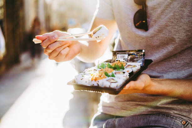 anonymous man eating sushi rolls on street in summer - junk food stock pictures, royalty-free photos & images