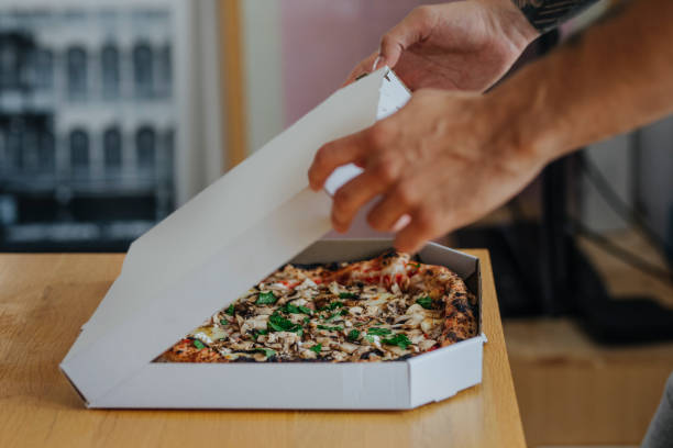 anonymous student opening a box of pizza he will eat during his study break - junk food stock pictures, royalty-free photos & images