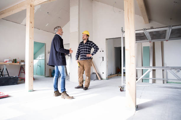 architect and construction worker discussing while standing in renovating house - home decoration stockfoto's en -beelden