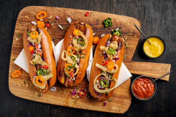artisan hot dogs in brioche rolls with pickles, onion and relishes. - food stock pictures, royalty-free photos & images
